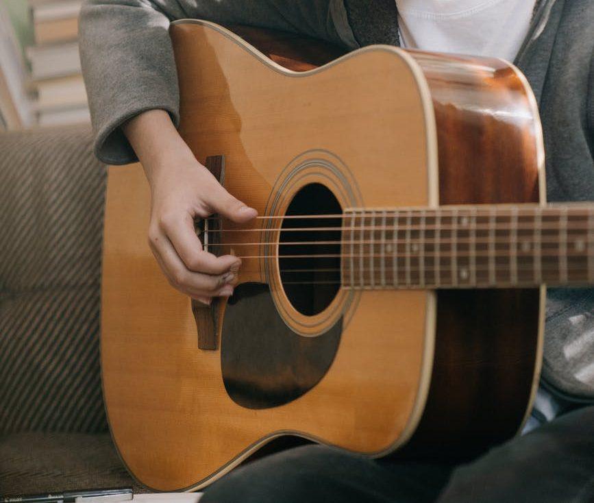 boy in gray and black crew neck shirt holding brown acoustic guitar